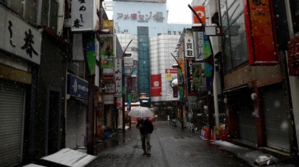 A man wearing a protective face mask, following an outbreak of the coronavirus disease, walks past on an empty street in theasnow fall in Tokyo