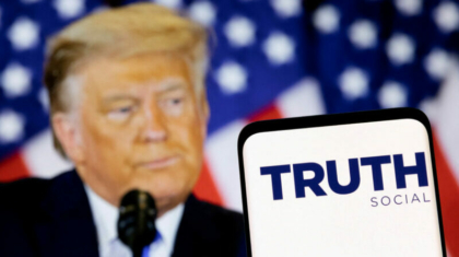 The Truth social network logo is seen on a smartphone in front of a display of former U.S. President Donald Trump in this picture illustration taken February 21, 2022. REUTERS/Dado Ruvic/Illustration/File Photo